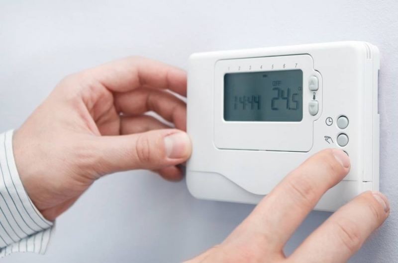 uomo che accende un termostato ambiente